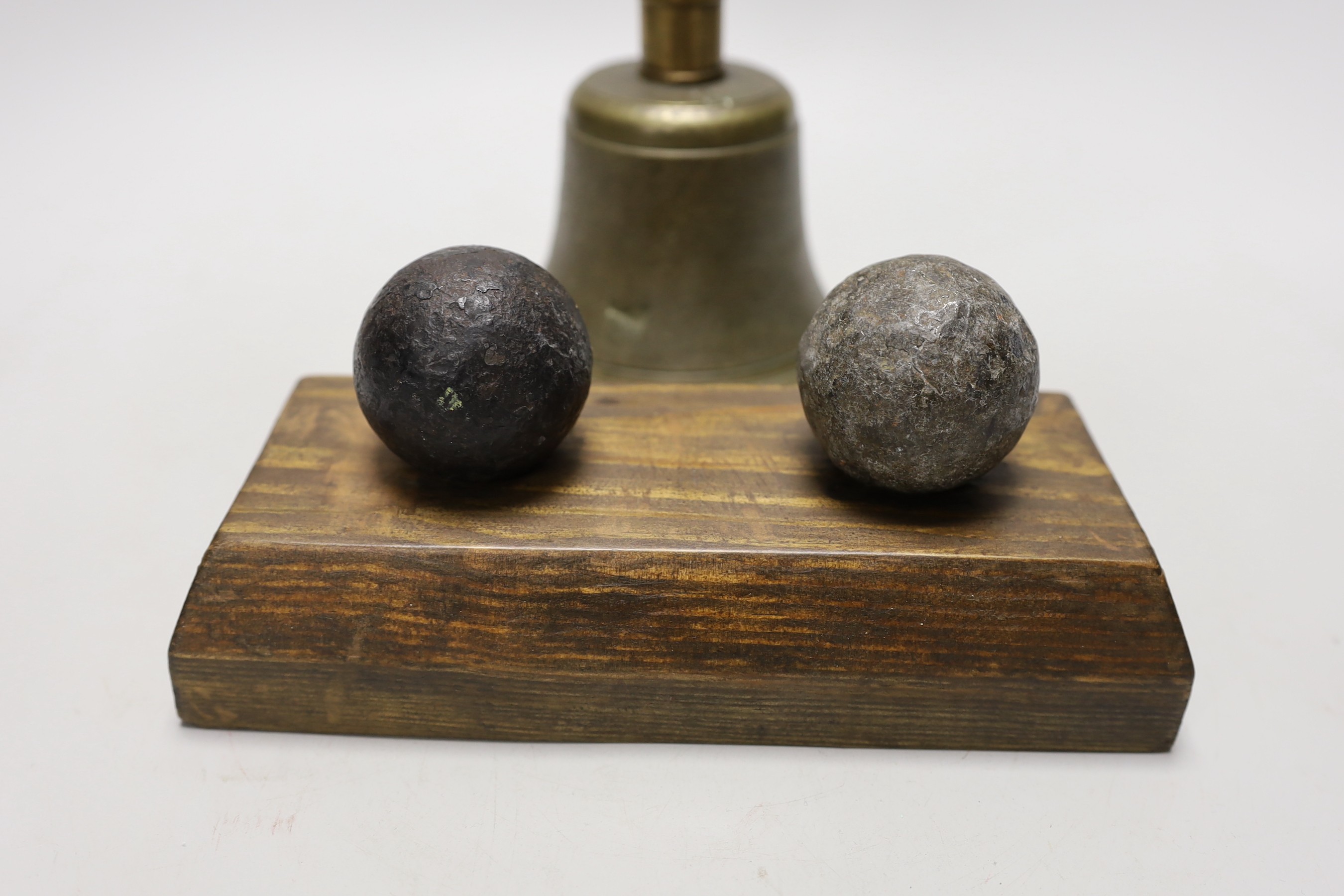 Two cannon balls, together with a brass hand bell marked A.R.P